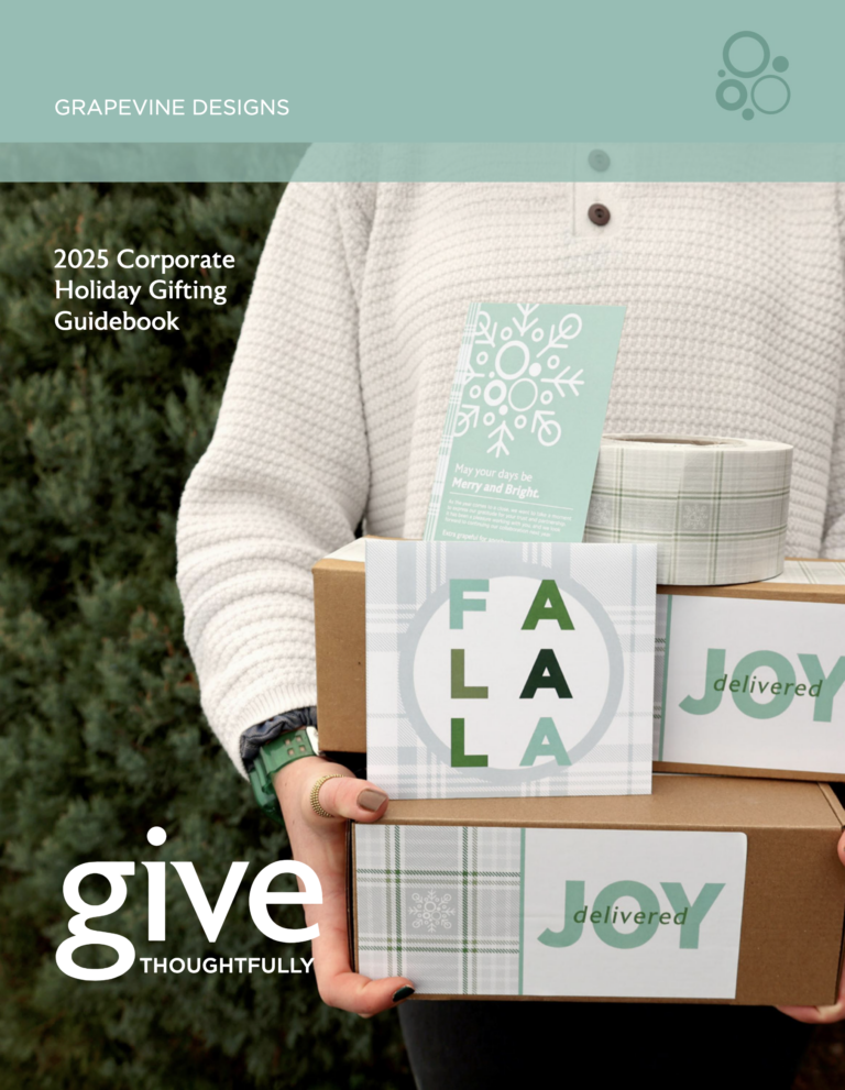 Person in a white sweater holds stacked gift boxes with holiday cards and plaid patterns. The text reads “2025 Corporate Holiday Gifting Guidebook” and “give thoughtfully” by Grapevine Designs.